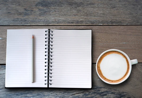 Notizbuch und Tasse Kaffee über Holztisch. — Stockfoto