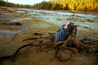 gövde ölü ağaç kökleri üzerinde oturan bir kadın önden görünümü. Derin depresyon kavramı