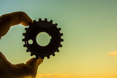 Bir ahşap cog güneşli gökyüzü arka plan üzerinde tutan erkek el.