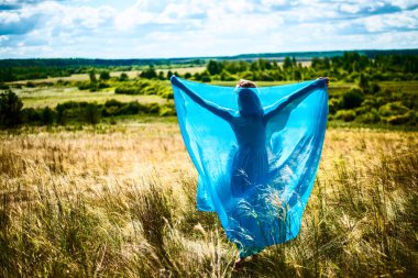 Buğday alan üzerinde yürüyen romantik ince kadın portresi, o parlak mavi zarif elbise giyiyor 