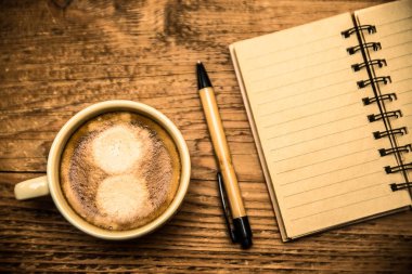 Üstten görünüm veya defter, kahve fincanı ve ahşap masa üzerinde boş denetim listesi 