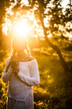 Güneş ışığı güzel genç kadın portresi. Kız holding çiçekler