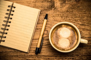 Üstten görünüm veya defter, kahve fincanı ve ahşap masa üzerinde boş denetim listesi 