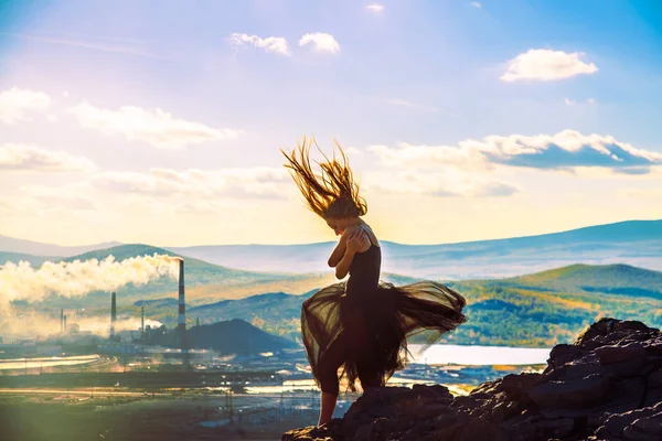 silhouette of dancing woman on stone of peak mountain.