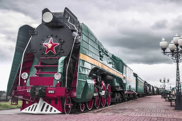 USSR steam green train with red star   at dramatic sky background. Omsk, Russia