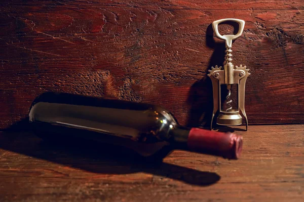 one Wine bottle and metal corkcrew  on wooden background. empty copy space