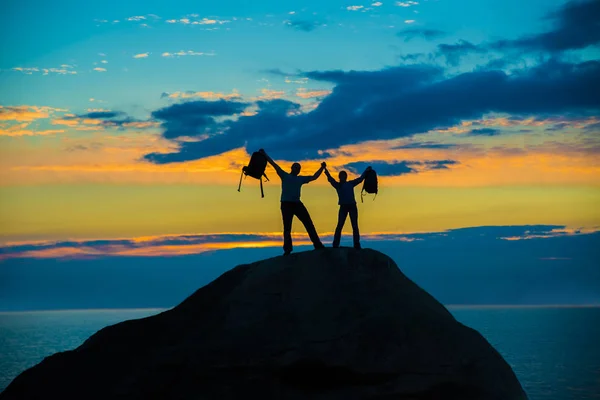 幸せなカップルは 上がる手で山のピークの上に一緒に立ってのシルエット — ストック写真