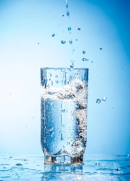 Água Derramando Vidro Foto Fundo Azul — Fotografia de Stock