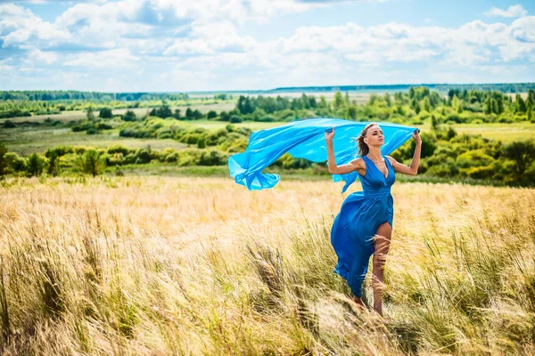 麦畑の上を歩いてロマンチックなスリムな女性の肖像画 彼女は明るいブルーのエレガントなドレスを着ています — ストック写真