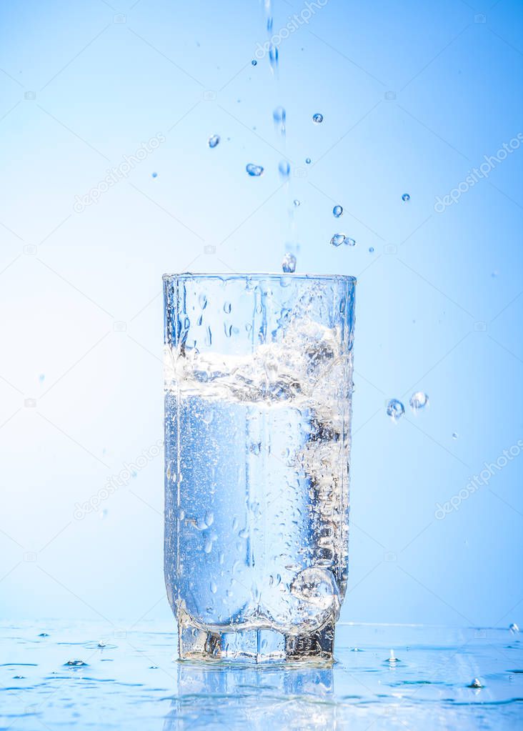 water pouring in glass, photo on the blue background.