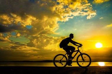Günbatımı gökyüzü bulutlu karşı bisiklet ile ve kıyı sportif turizm kişini görüntüsünü 