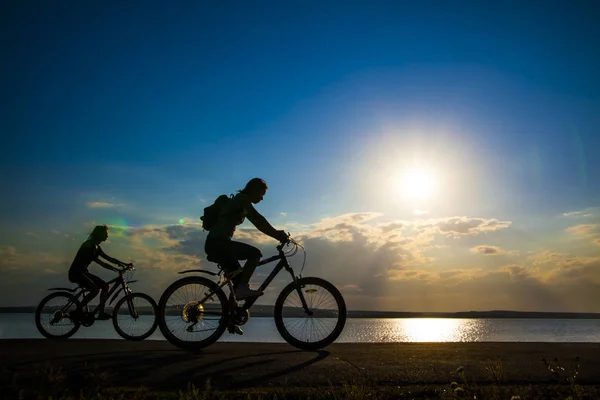 空的空间 运动的朋友在自行车在日落 骑自行车的人沿着海岸 体育在自然背景 — 图库照片