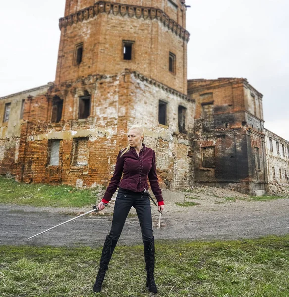 blond woman warrior with a sword standing by castle.