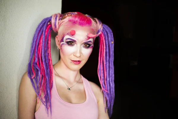 Portrait of a young woman with pink and purple dreadlocks. colorful freak girl with ped eyes and horns