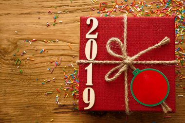 Kırmızı hediye kutusu ve kahverengi şerit ile ahşap rustik ahşap numaraya 2019. boş kopya alanı yazıt veya nesneler için