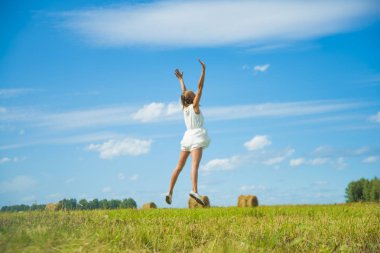 Mavi arka planda sevinç için atlayan sarışın kadın.