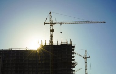 Endüstriyel İnşaat vinçleri ve Binalar siluetleri gündoğumu sırasında