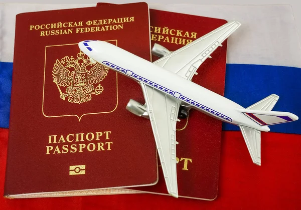 Two russian  passports on russian flag background and plane toy. tourism. journey