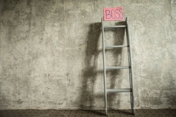 Career ladder with paper with boss sign board on gray concrete wall. Business success concept