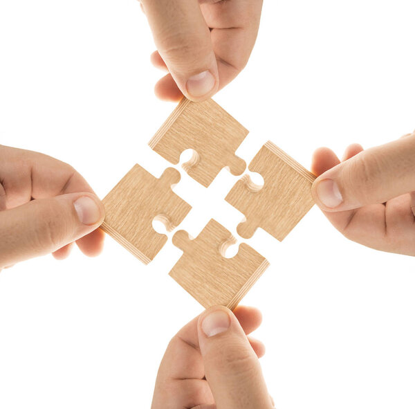 Пальцы держат кусочки коричневой деревянной головоломки. Изолированный на белом фоне
. 