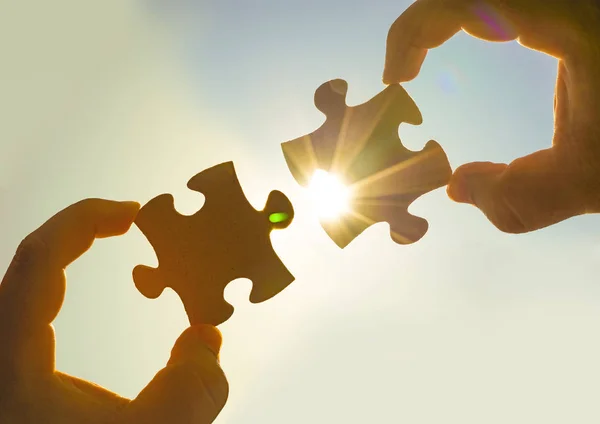 hands  with  puzzle pieces with sky background.