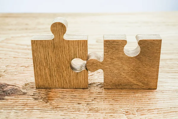 two  wooden puzzle pieces  on table. concept of connection people
