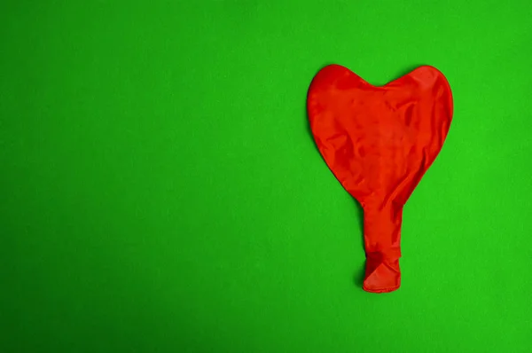 red deflated balloon isolated on green  background.