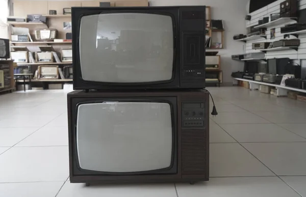 two old, vintage, aged television receivers inside room
