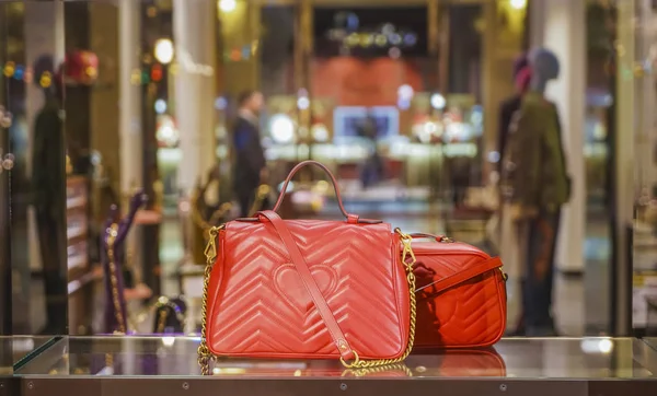 two Luxury red handbags in store showcase in Milan, Italy.