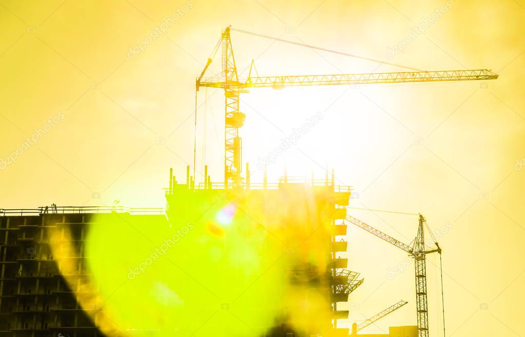 Industrial construction cranes and buildings silhouettes during sunrise