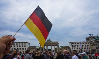 Berlin, Almanya - 13 Temmuz 2018: bayrak Brandenburg Kapısı ayrıntılarını arka plan üzerinde tutan kişi bir 18. yüzyıldan kalma neoklasik anıtıdır. Kapıyı Prusya kralı Frederick William II tarafından barış işareti olarak görevlendirildi.