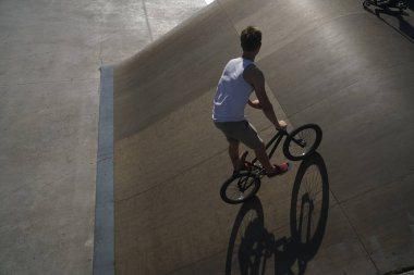 Yaz Sporu. Onun BMX aşırı bisiklet ile Freestyle hüner gösteren genç çocuk. Beton alanda genç bisiklet binici. güneşli gün ve gölge