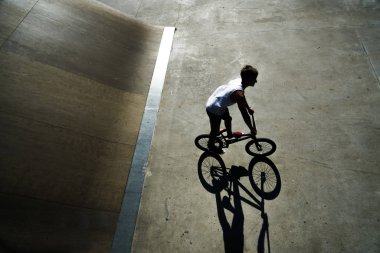 Yaz Sporu. Onun BMX aşırı bisiklet ile Freestyle hüner gösteren genç çocuk. Beton alanda genç bisiklet binici. güneşli gün ve gölge.
