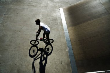 Yaz Sporu. Onun BMX aşırı bisiklet ile Freestyle hüner gösteren genç çocuk. Beton alanda genç bisiklet binici. güneşli gün ve gölge.