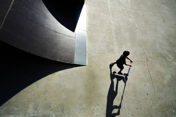 Kid to ride scooter. Boy on kick scooter making  a trick and enjoying his riding by skate in the skate park