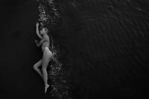 顶部视图 美丽的年轻女子 金色卷曲的长发躺在沙滩上潮湿的沙滩上 — 图库照片