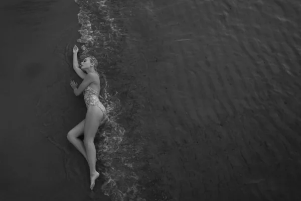 顶部视图 美丽的年轻女子 金色卷曲的长发躺在沙滩上潮湿的沙滩上 — 图库照片