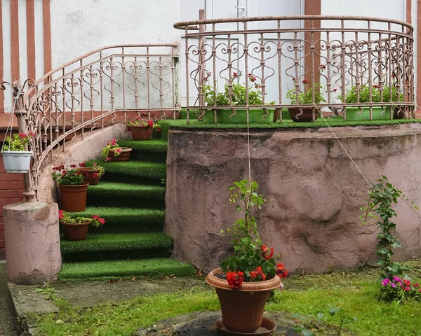 circular concrete steps of stairway with flowers in pots  in a green garden