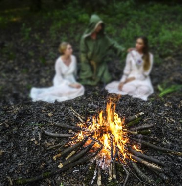 Karanlık ormandaki ateşe bakan iki güzel cadı. Sihirbaz. ateşe odaklanın 