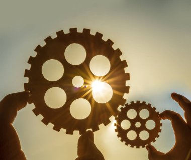 Erkek holding metal Dişliler - gökyüzü arka plan eller. iş, etkileşim, ekip çalışması fikir