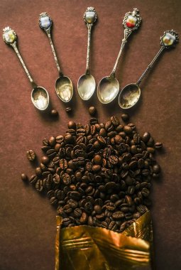kahve çekirdekleri çevresinde birçok antika kaşık. üzerinde izole kahverengi zemin 