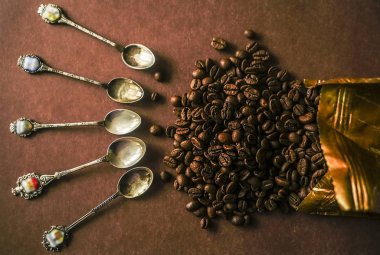 kahve çekirdekleri çevresinde birçok antika kaşık. üzerinde izole kahverengi zemin 