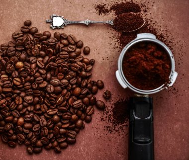 Cafe koyu kahverengi dokulu arka plan üzerinde siyah kahve çekirdekleri. kahve makinesi. üstten görünüm. tam kaşık