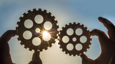 Erkek holding metal Dişliler - gökyüzü arka plan eller. iş, etkileşim, ekip çalışması fikir