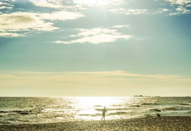 Gün batımında sahilde yürüyüş köpek ve runniung adam siluet