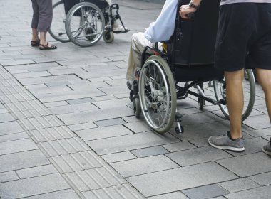Sokakta tekerlekli sandalyeli engelliler. yüz yok. Tekerlekli sandalyede engelli kadına yardım erkek