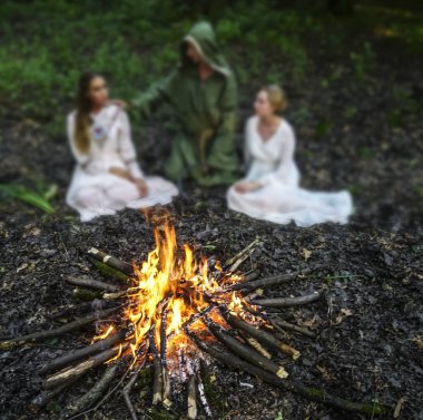 Karanlık ormandaki ateşe bakan iki güzel cadı. Sihirbaz. ateşe odaklanın 