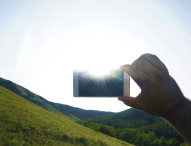Akıllı telefon ve mavi gökyüzü. erkek eli boş ekranlı akıllı telefon tutarak. 