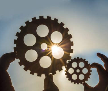 Erkek holding metal Dişliler - gökyüzü arka plan eller. iş, etkileşim, ekip çalışması fikir