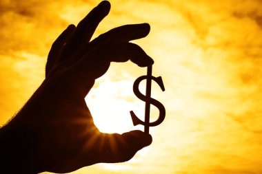 Dolar işareti silüeti gökyüzü arka plan tutan el